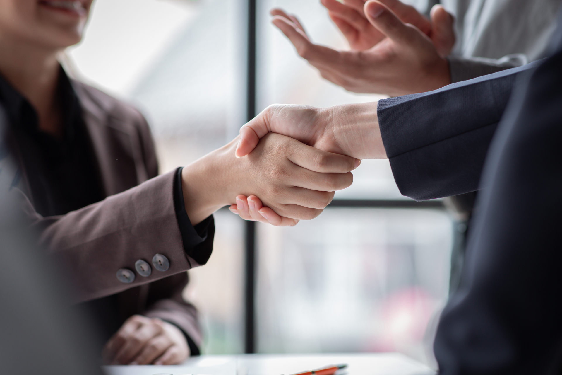 Two professionals shaking hands across an office desk